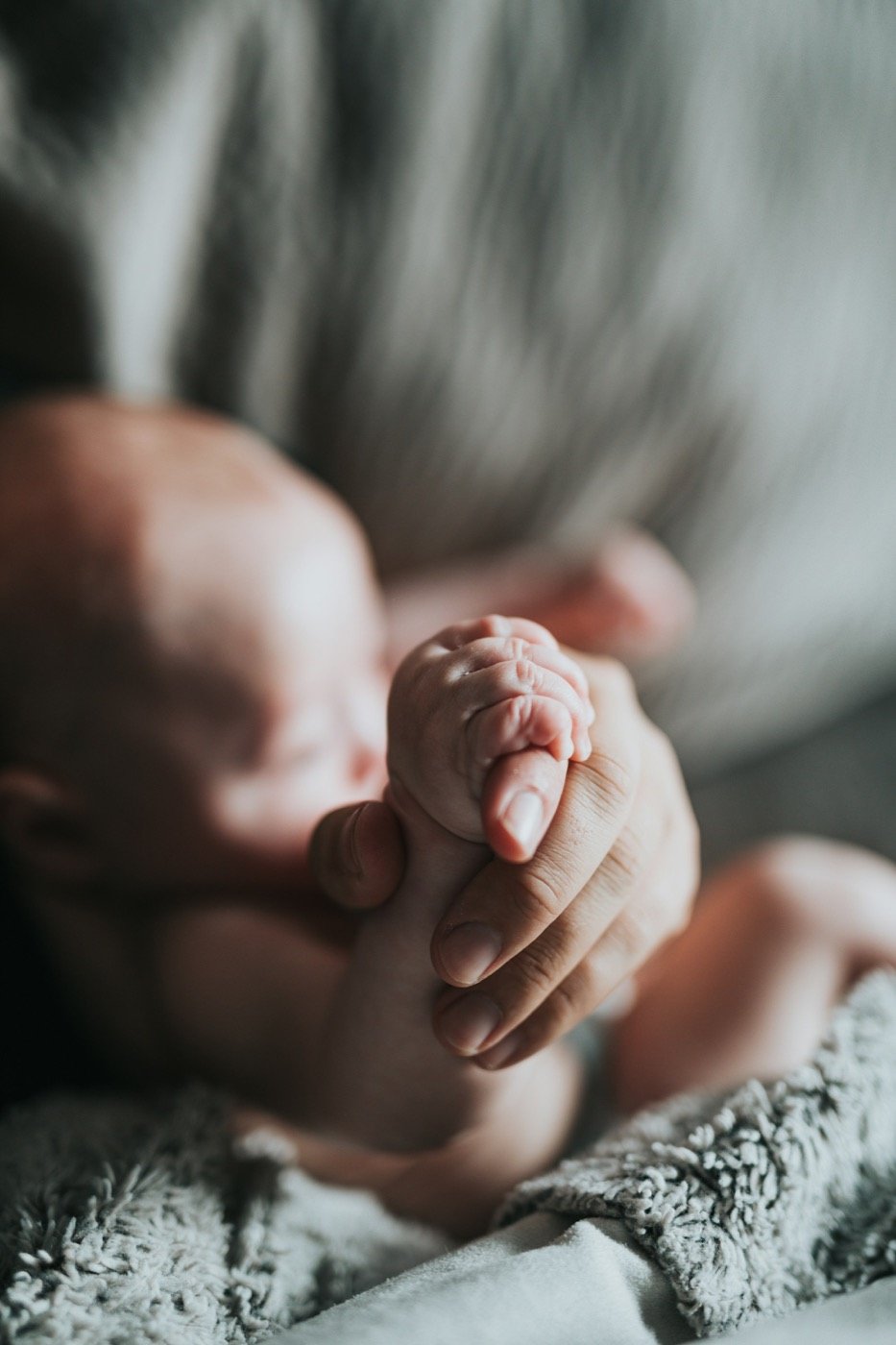 Newborn hand holding an adult finger