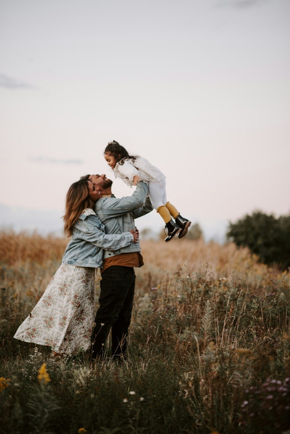 Parents lifting their child in a field