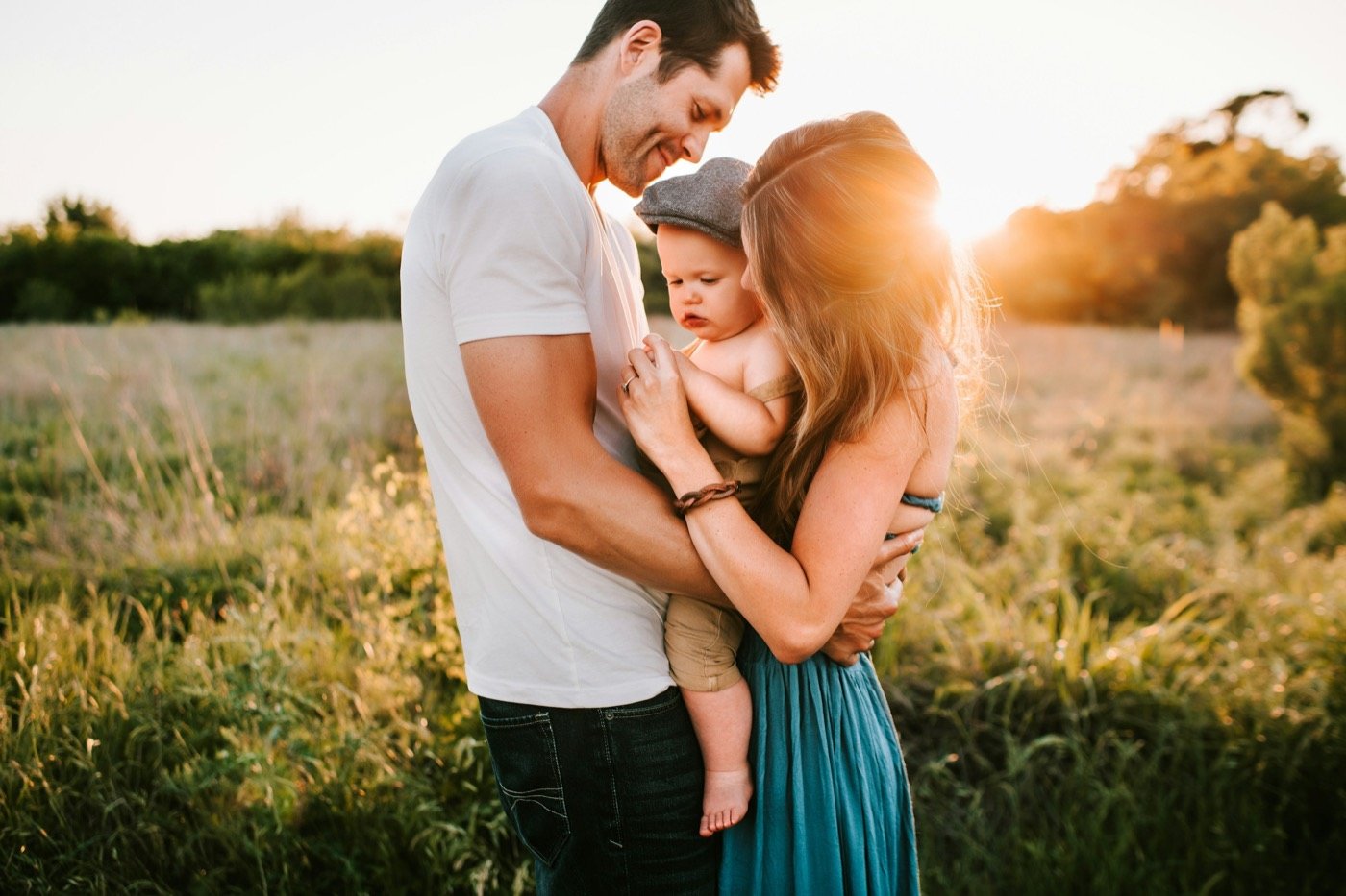 Parents holding their baby together in warm evening light