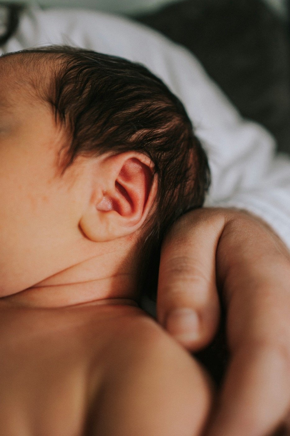 Close detail of a newborn's ear and curled hand